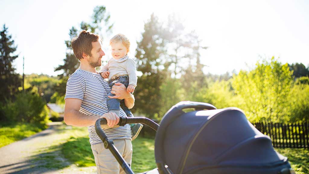 young man holding baby and pram