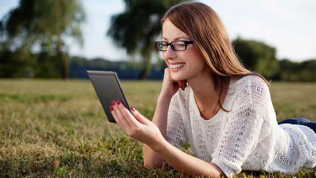 woman in field reads ebook