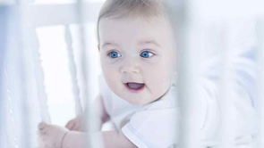 baby looking out of a cot