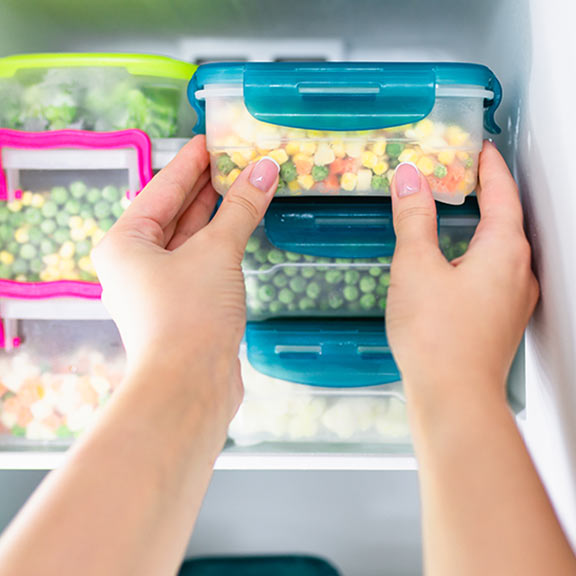 person putting food into a freezer sq