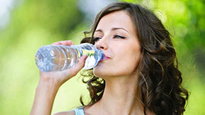 woman drinking water from plastic bottle