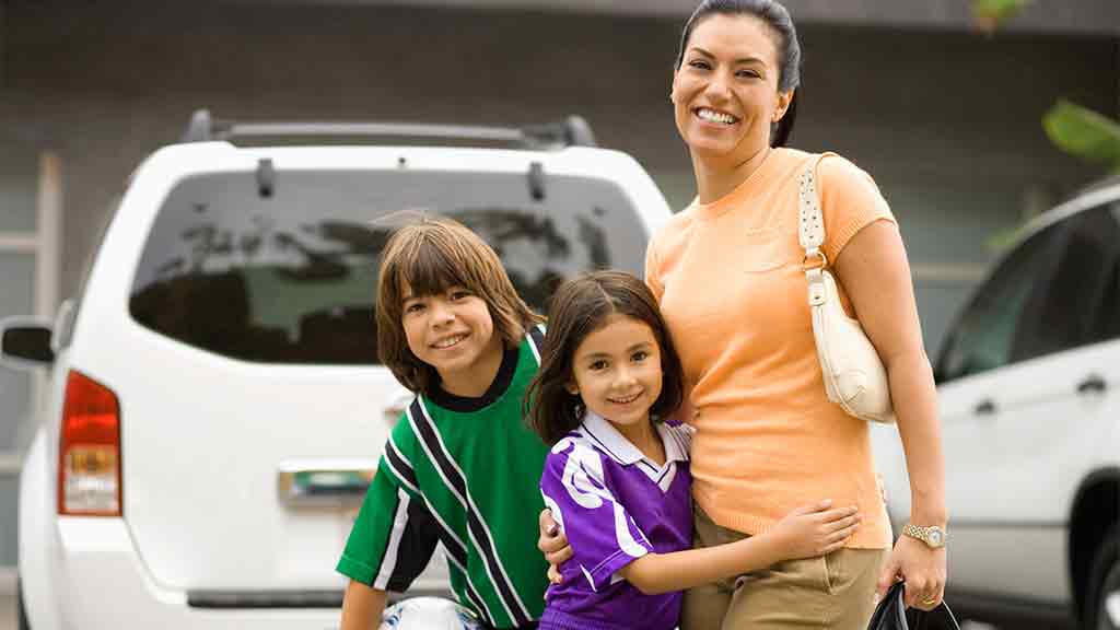 mother and two kids in front of car