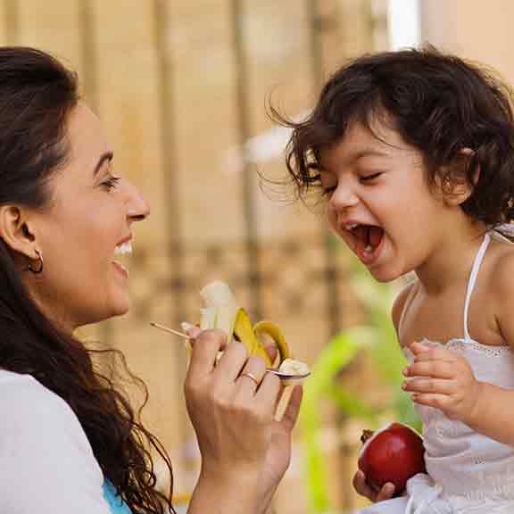 mother feeding her daughter square